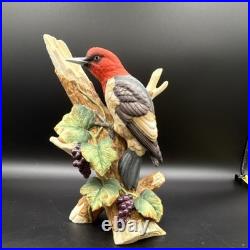 Porcelain bird figurine depicting a red-headed bird on branch with grape clusters