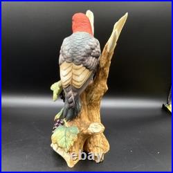 Porcelain bird figurine depicting a red-headed bird on branch with grape clusters