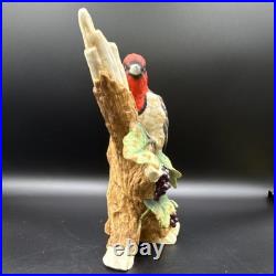 Porcelain bird figurine depicting a red-headed bird on branch with grape clusters