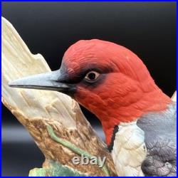 Porcelain bird figurine depicting a red-headed bird on branch with grape clusters
