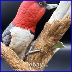 Porcelain bird figurine depicting a red-headed bird on branch with grape clusters
