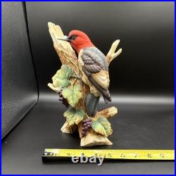 Porcelain bird figurine depicting a red-headed bird on branch with grape clusters