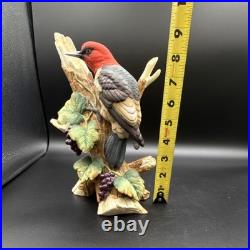 Porcelain bird figurine depicting a red-headed bird on branch with grape clusters