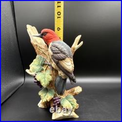 Porcelain bird figurine depicting a red-headed bird on branch with grape clusters