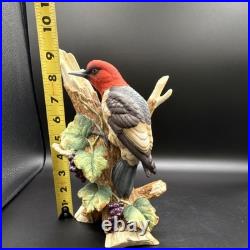 Porcelain bird figurine depicting a red-headed bird on branch with grape clusters